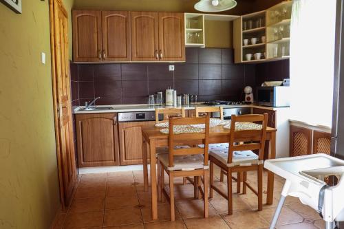 uma cozinha com armários de madeira e uma mesa e cadeiras em Forest Luxury Apartman em Dorogháza