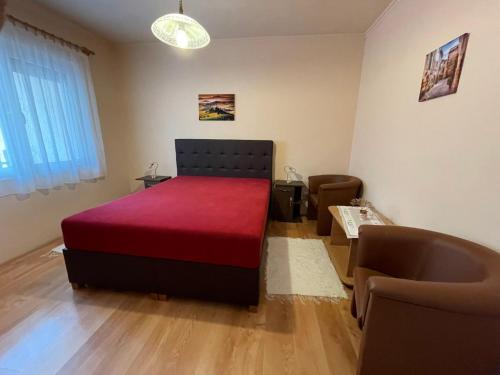 1 dormitorio con cama roja y sofá en Vámos Apartman, en Bük