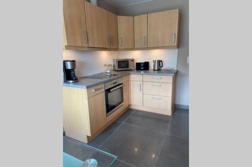 a small kitchen with wooden cabinets and appliances at Ferienwohnung Zwischen Eider u. Elbe in Eddelak