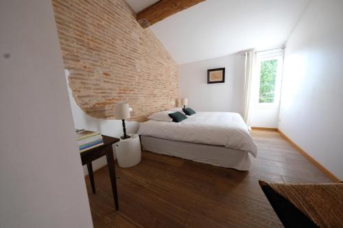 a bedroom with a bed and a brick wall at Bastide le Petit Clos - les 2 Gîtes in Perpignan