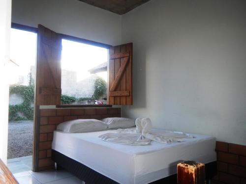 a bedroom with a white bed with a window at Pousada Segredo in Bonito