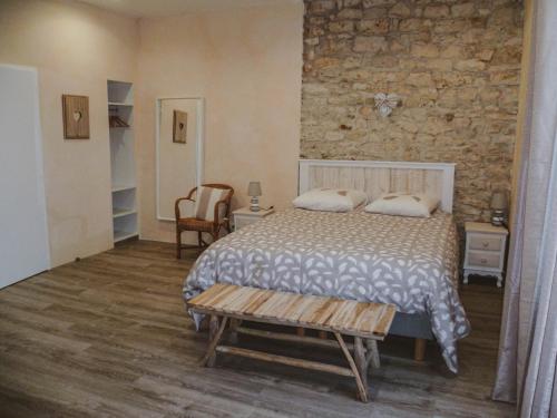 una camera da letto con un letto e un muro di pietra di LA LAUJÈRE Chambres d'hôtes ROMANCE a La Caillère
