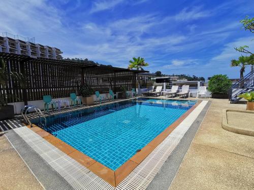 a large swimming pool with blue chairs next to a building at Patong Princess in Patong Beach