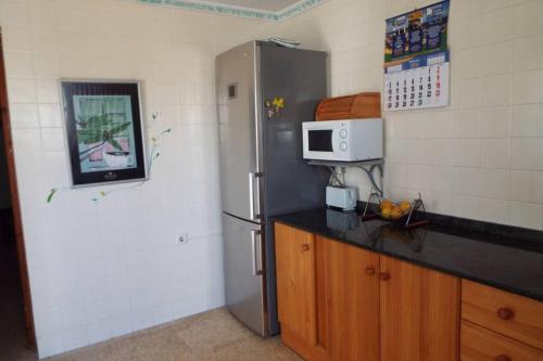 uma cozinha com um frigorífico de aço inoxidável e um micro-ondas em The Beach House Denia -- Casa en primera línea de playa - Denia em Denia