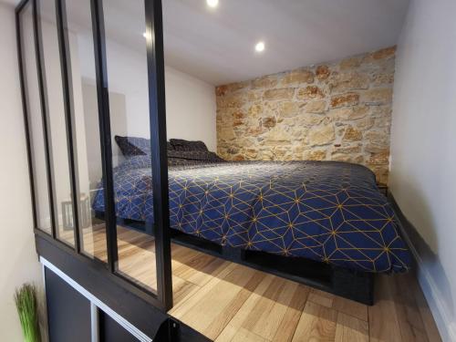 1 dormitorio con cama y pared de piedra en Studio atypique dans bel immeuble de 1820, en Fumel