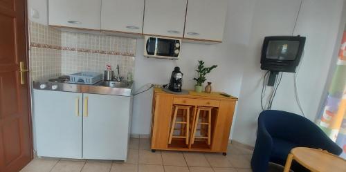 una pequeña cocina con fregadero y TV en Elo Apartman, en Csokonyavisonta