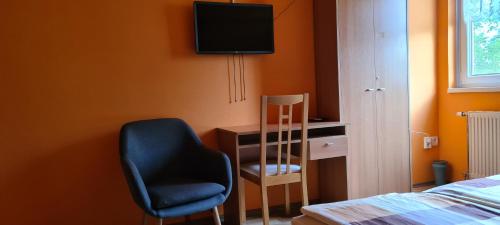 a bedroom with a chair and a desk and a television at Hajas Família Kiadó Szobák in Balatonmáriafürdő