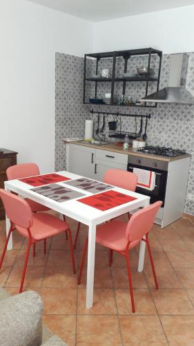 a kitchen with a white table and red chairs at MAX and SUN parking privato nel prezzo in Sanremo