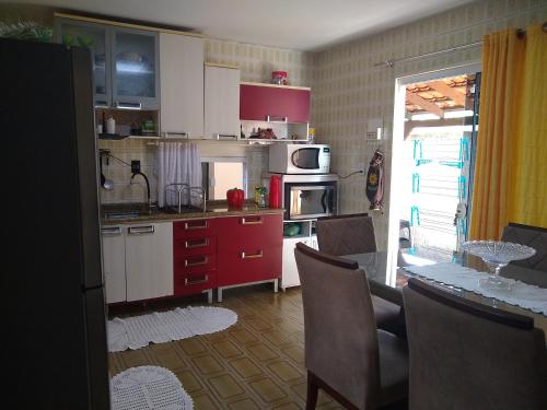 a kitchen with red and white cabinets and a table at Enseada encantada in Porto Belo