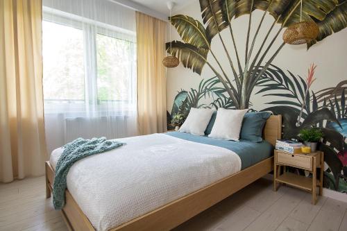 a bedroom with a bed with a large plant on the wall at W&K Apartments - Energy Suite - Faktura VAT, Parking in Koszalin