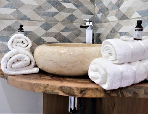 La salle de bains est pourvue d'un lavabo et de serviettes sur une table. dans l'établissement A l'ombre des remparts, à Carcassonne