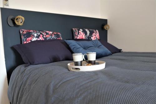 Una cama con una bandeja con dos tazas. en A l'ombre des remparts, en Carcassonne