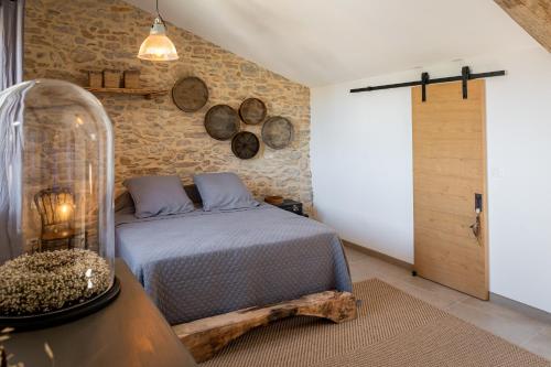 een slaapkamer met een bed en een stenen muur bij Mas des Aïeux in Laudun