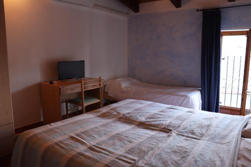 a bedroom with a bed and a desk with a television at Le Camere Dell'Ancora in Monzambano