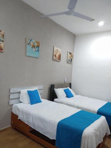 two beds in a room with white walls at Casa Esencia in Cozumel