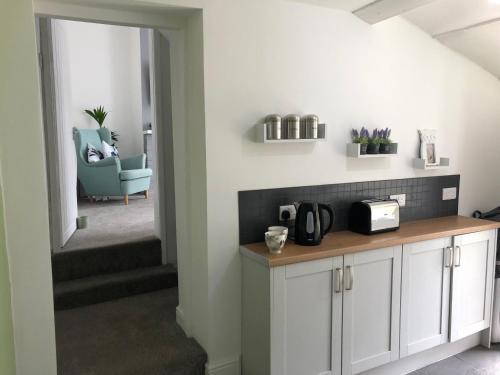 a kitchen with white cabinets and a blue chair at Jasmyne Cottage in Wainfleet All Saints