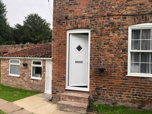 a brick house with a white door and two windows at Jasmyne Cottage in Wainfleet All Saints