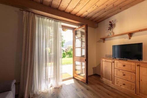 a living room with a television and a sliding glass door at Biochalet Märkl in Bad Kleinkirchheim