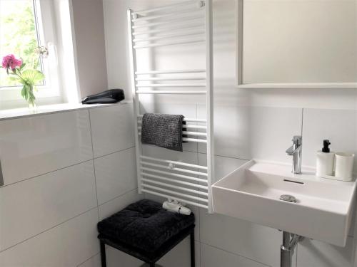 a white bathroom with a sink and a stool at urbanAPARTMENT No.1 Memmingen in Memmingen