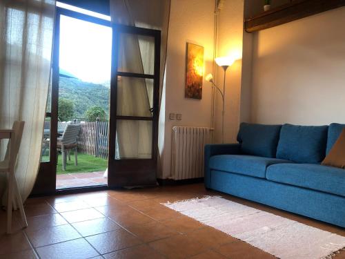 a living room with a blue couch and a sliding glass door at Casa les Pomeretes in El Figaró