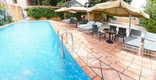 a swimming pool with chairs and umbrellas and a table at Tulia Boutique Hotel & Spa in Arusha