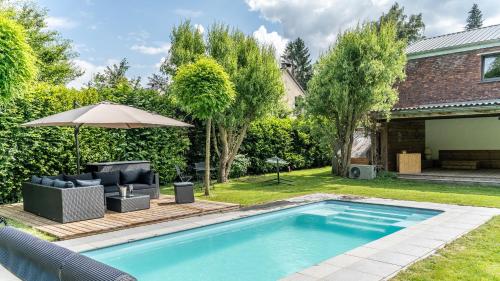 un patio trasero con piscina y sombrilla en Paradis Secret, en Beyne-Heusay