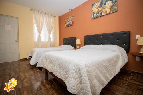 two beds in a bedroom with orange walls at Hotel Jatziri in San Juan Teotihuacán