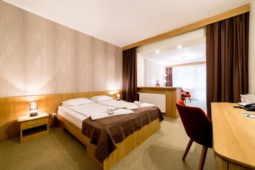 a hotel room with a bed and a desk at Hotel Muresul Health Spa in Sovata
