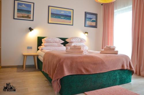 a bedroom with a bed with stacks of towels on it at Pod Brzozami Apartamenty 5 Mórz in Ustronie Morskie
