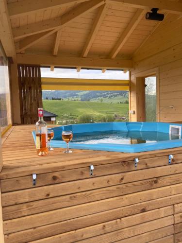 a hot tub in a wooden house with a glass of wine at Casa Bunicii in Şarul Dornei