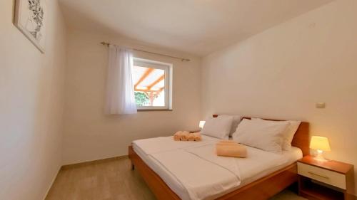 a bedroom with a bed with white sheets and a window at Apartments Dario in Medulin