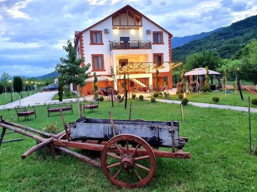 an old cart sitting in the grass in front of a house at Karse in Ambrolauri