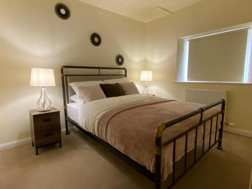 a bedroom with a bed and two lamps and a window at Rattlebeck Farm Cottage and Hot Tub PET FRIENDLY in Welton