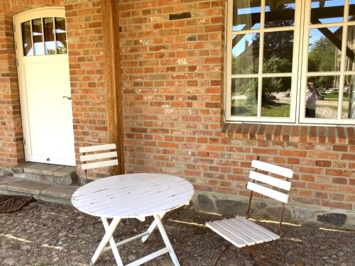 a table and two chairs next to a brick building at Gutshaus Lexow in Lexow