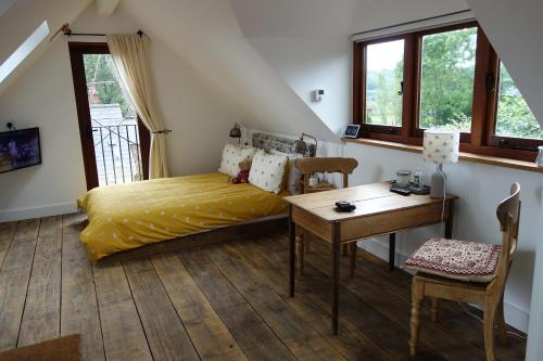 a bedroom with a bed and a desk and windows at The Roost in Semley