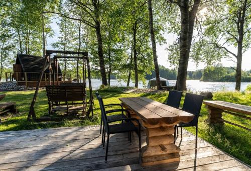 una mesa de madera y sillas en una terraza con parque infantil en Laawu Kultainkoski, en Kotka