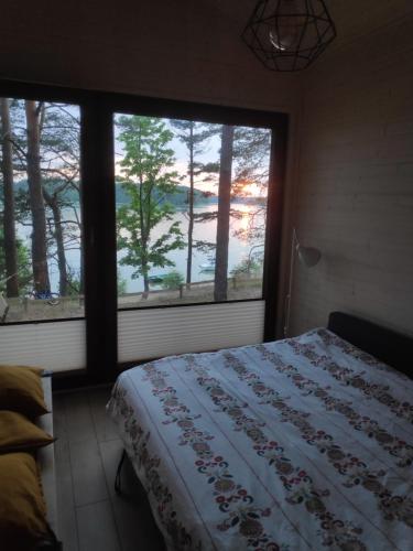 ein Schlafzimmer mit einem Bett und einem großen Fenster in der Unterkunft Zakątek Wdzydze nad samym jeziorem - pierwsza linia in Borsk