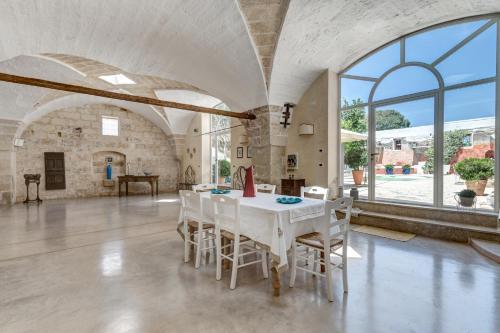 una sala da pranzo con tavolo e sedie bianchi di Masseria La Macchiola & Corti del Mito a Spongano