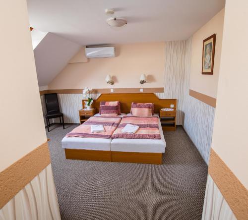 a bedroom with a bed with pink pillows at Tinódi Fogadó in Sárvár