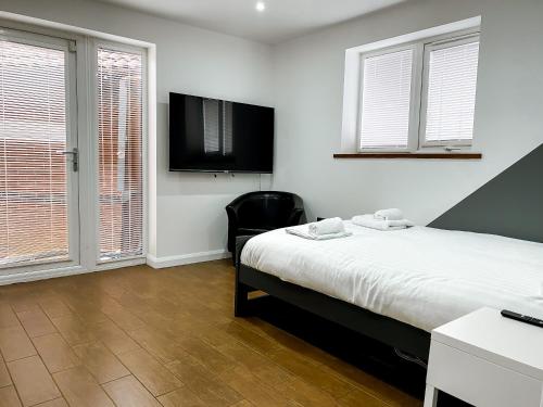 a bedroom with a bed and a chair and windows at 4 bed family home wifi, netflix, parking, close to wicksteed park in Kettering