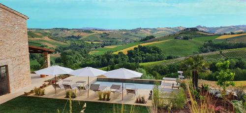 a patio with white umbrellas and a pool with a view at Lemonvilla - Rustico in Panoramalage in Castignano
