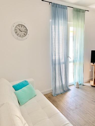 a white couch in a room with a clock on the wall at Apartmani Stupin Čeline in Podglavica