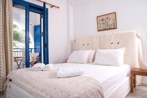 a bedroom with a large white bed and a balcony at Kanellis Studios in Avlemonas
