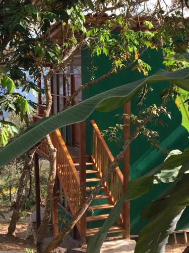 a house with a wooden staircase in front of a tree at Indano Art Lodge in Lamas