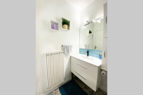 une salle de bain blanche avec un lavabo et un miroir dans l'établissement Charmant appartement avec vue sur les montagnes, à Annecy