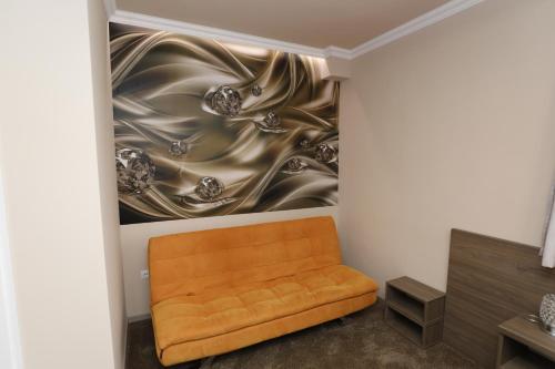 an orange couch in a room with a painting at Tinódi Fogadó in Sárvár