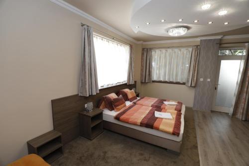 a bedroom with a bed and two windows at Tinódi Fogadó in Sárvár