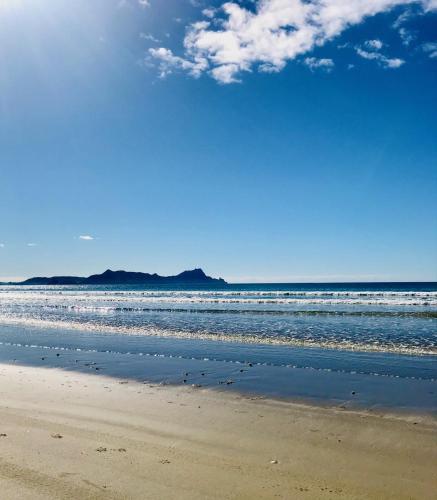 a sandy beach with waves in the ocean at Wairimu View Lodge in Waipu