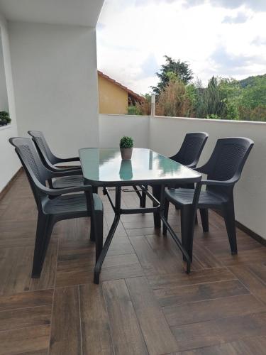 a glass table and four chairs on a balcony at Fiesta Apartman in Miskolctapolca