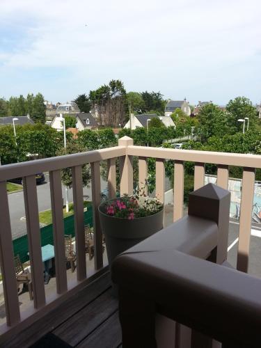 a balcony with a bench and a pot of flowers at Hôtel L'ideal le Mountbatten in Arromanches-les-Bains